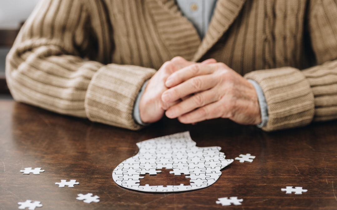 cropped view of senior man with a puzzle on a table